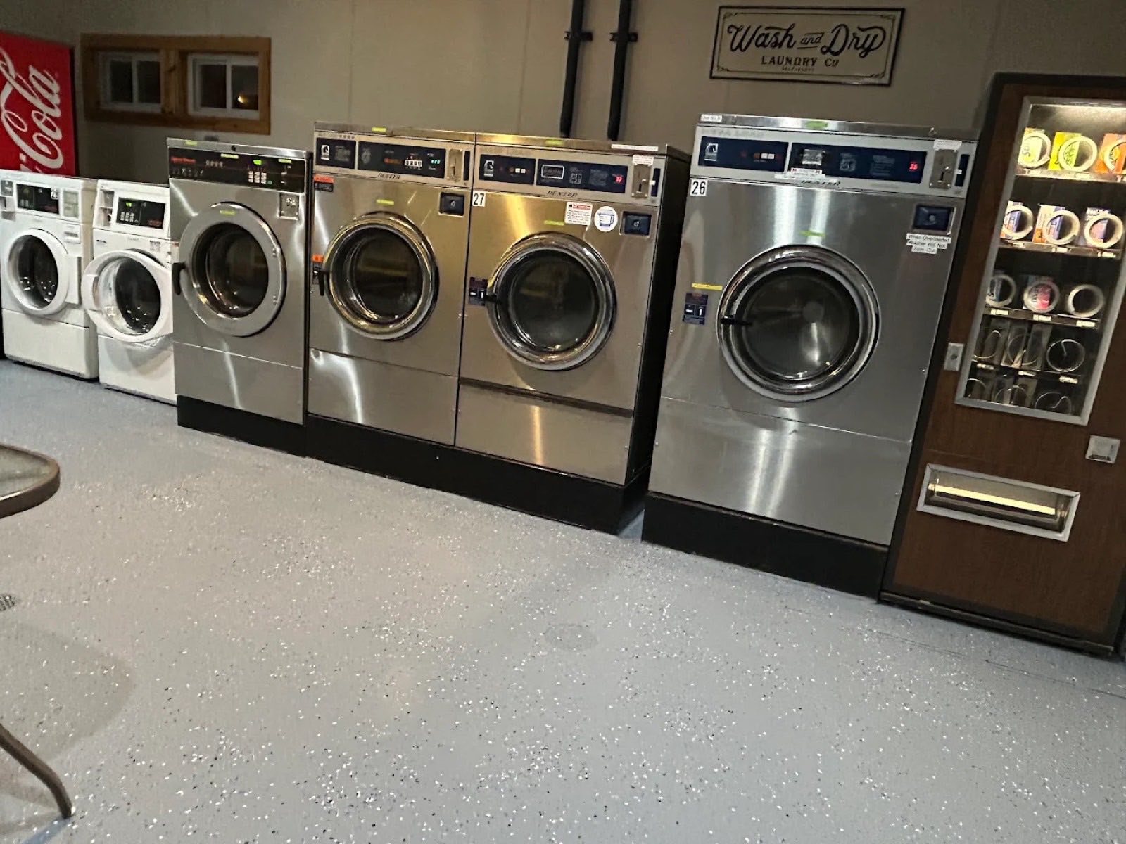 Row of coin-operated self-serve washers at Bayside Coin Laundry in St. Ignace, from Speed Queen front-loaders to large-capacity Dexter Maxi Load machines